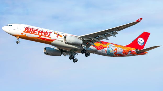 A Sichuan Airlines plane with vibrant artwork is flying in clear blue skies.