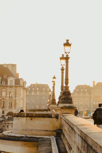 Elegant street lamps on a historic bridge in Paris with a warm sunset glow.