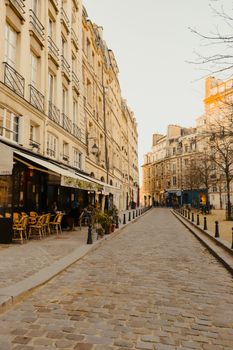 A picturesque cobblestone street lined with classic European architecture in warm daylight.