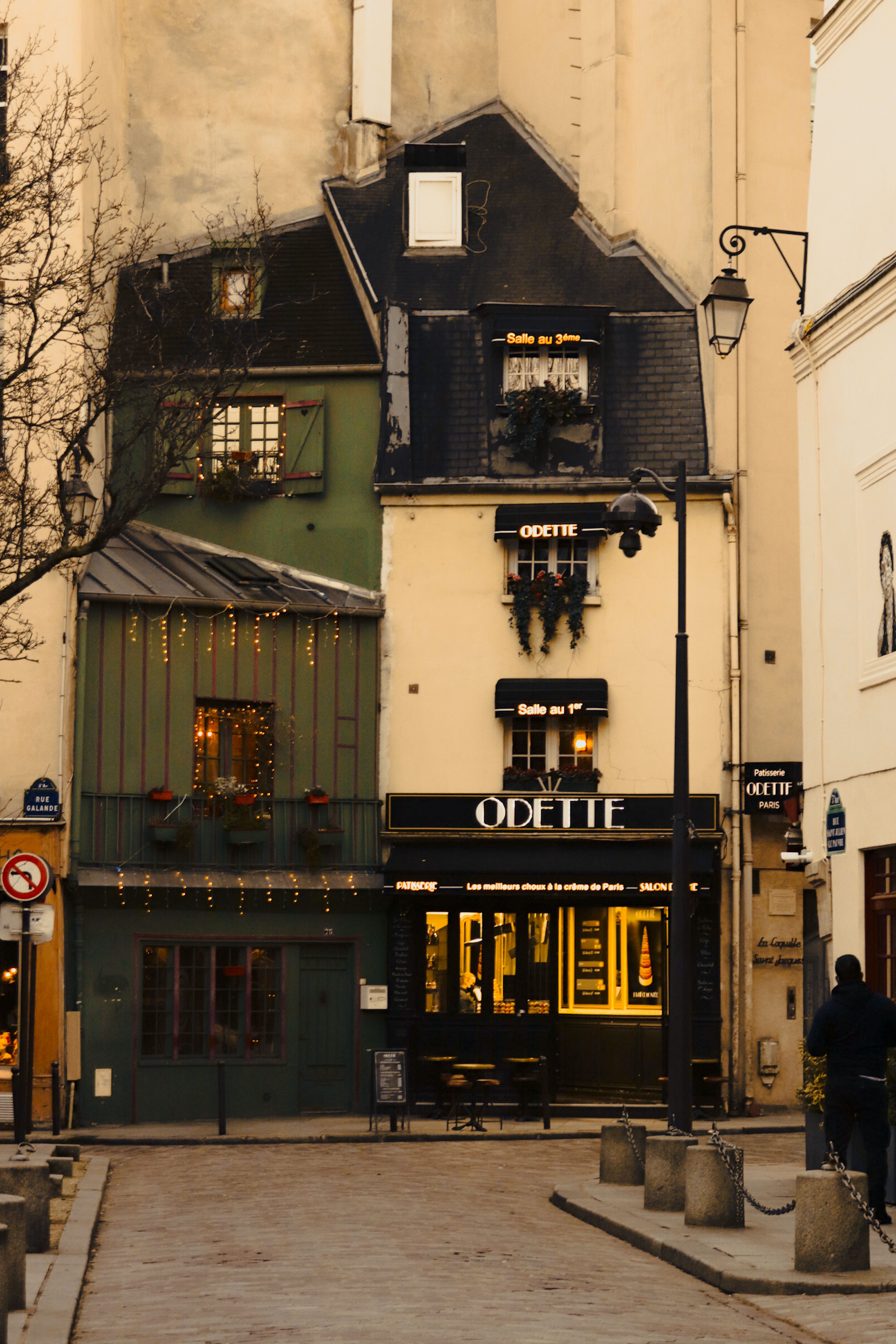 Quaint Parisian café Odette during winter, adorned with festive lights in a narrow street.