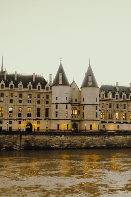 A grand historic castle with gothic architecture illuminated at twilight by the river.