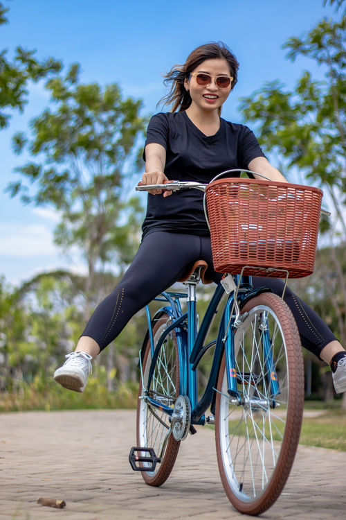 Free A woman joyfully rides a bicycle in a park with trees in Ho Chi Minh City, Vietnam. Stock Photo