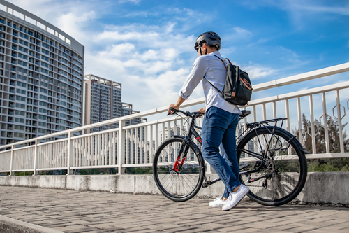 Free Man with bike on bridge in urban setting wearing helmet and backpack. Stock Photo