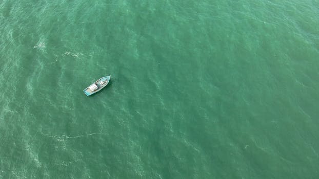 A drone captures a solitary boat navigating the green waters of Baía Formosa, Brazil.