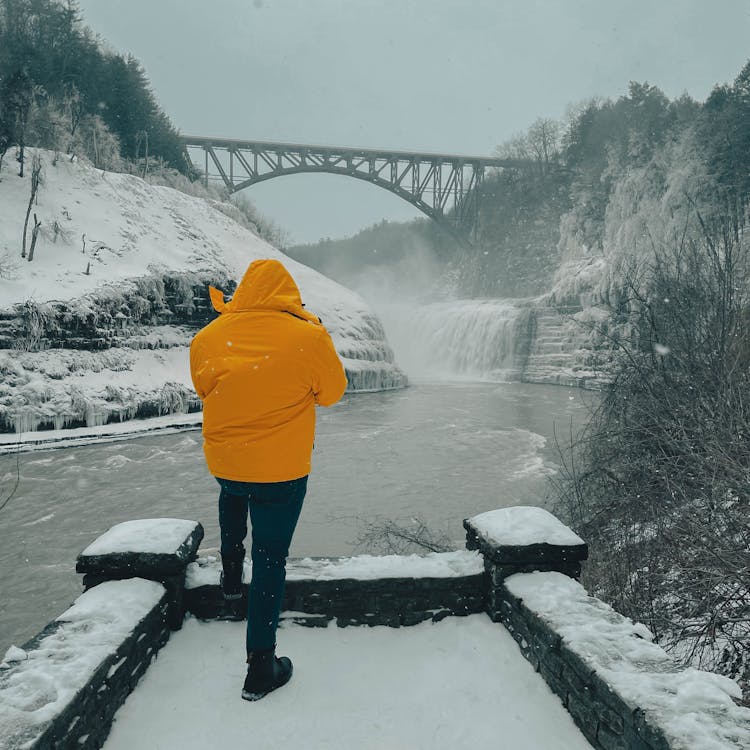 Man By The River In A Mountain Valley In Winter 