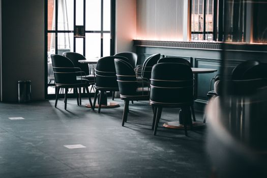 Elegant and cozy coffee shop dining area with stylish black chairs and wooden tables.
