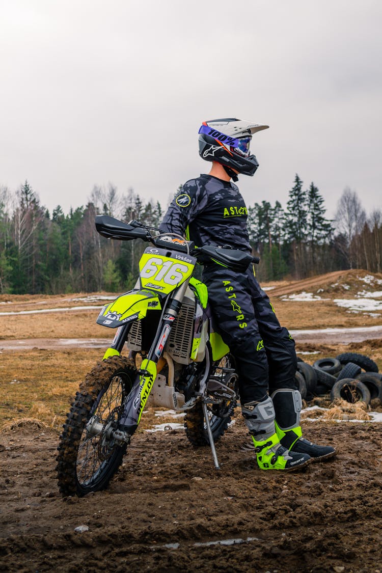 A Person In His Full Safety Gear Costume Leaning On His Motorbike