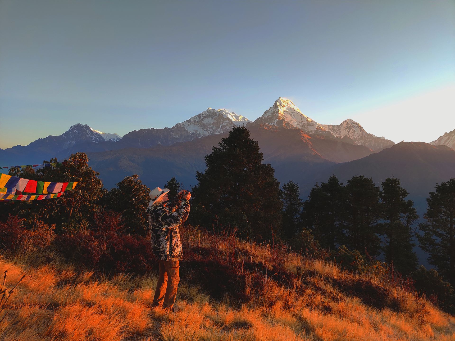 A person taking a photo of the Annapurna mountain range at sunrise in Ghode Pani, Nepal.