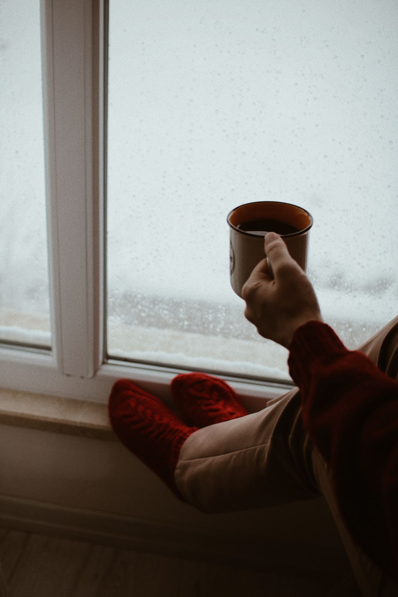 red socks and a warm drink by a snowy window