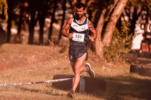 A male athlete participates in an outdoor running competition, showing determination and speed.