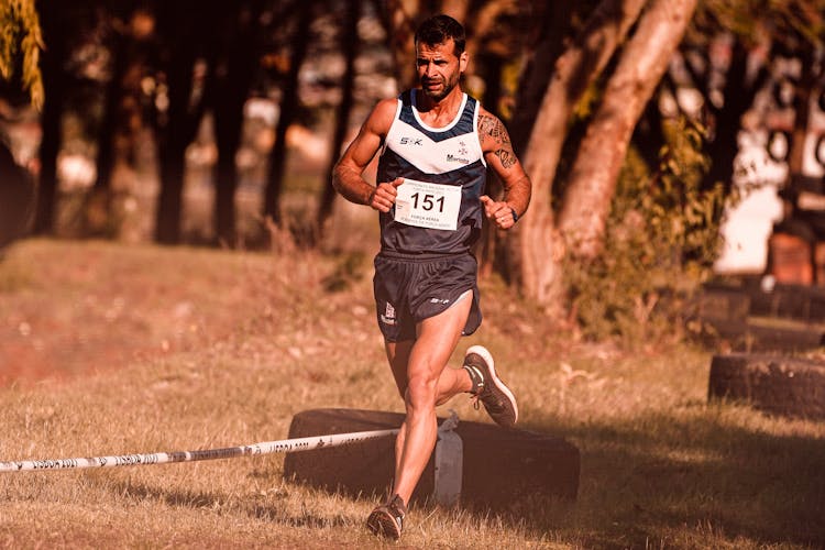 Man In Black Tank Top And Shorts Running On The Field