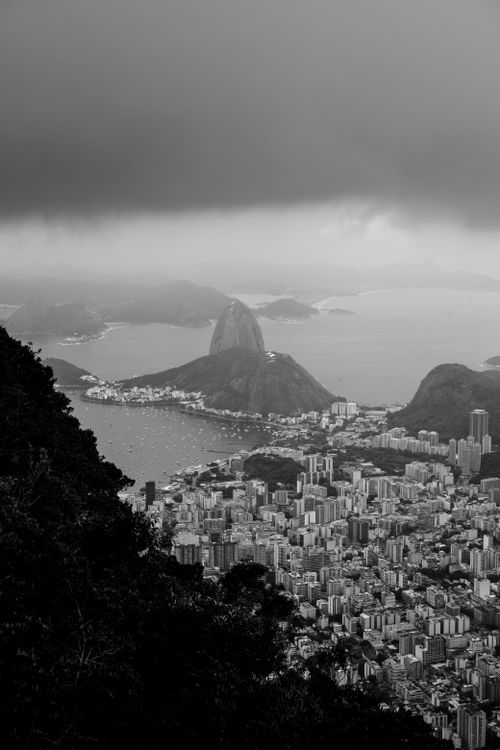 Free A breathtaking black and white aerial view of Rio de Janeiro's skyline featuring the iconic Sugarloaf Mountain beneath stormy clouds. Stock Photo
