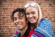 一对快乐的年轻夫妇在圣路易斯奥比斯波的一堵砖墙前相拥