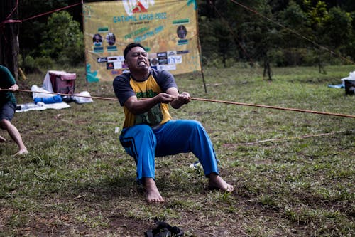 Man Playing Tug of War on Grass Field 