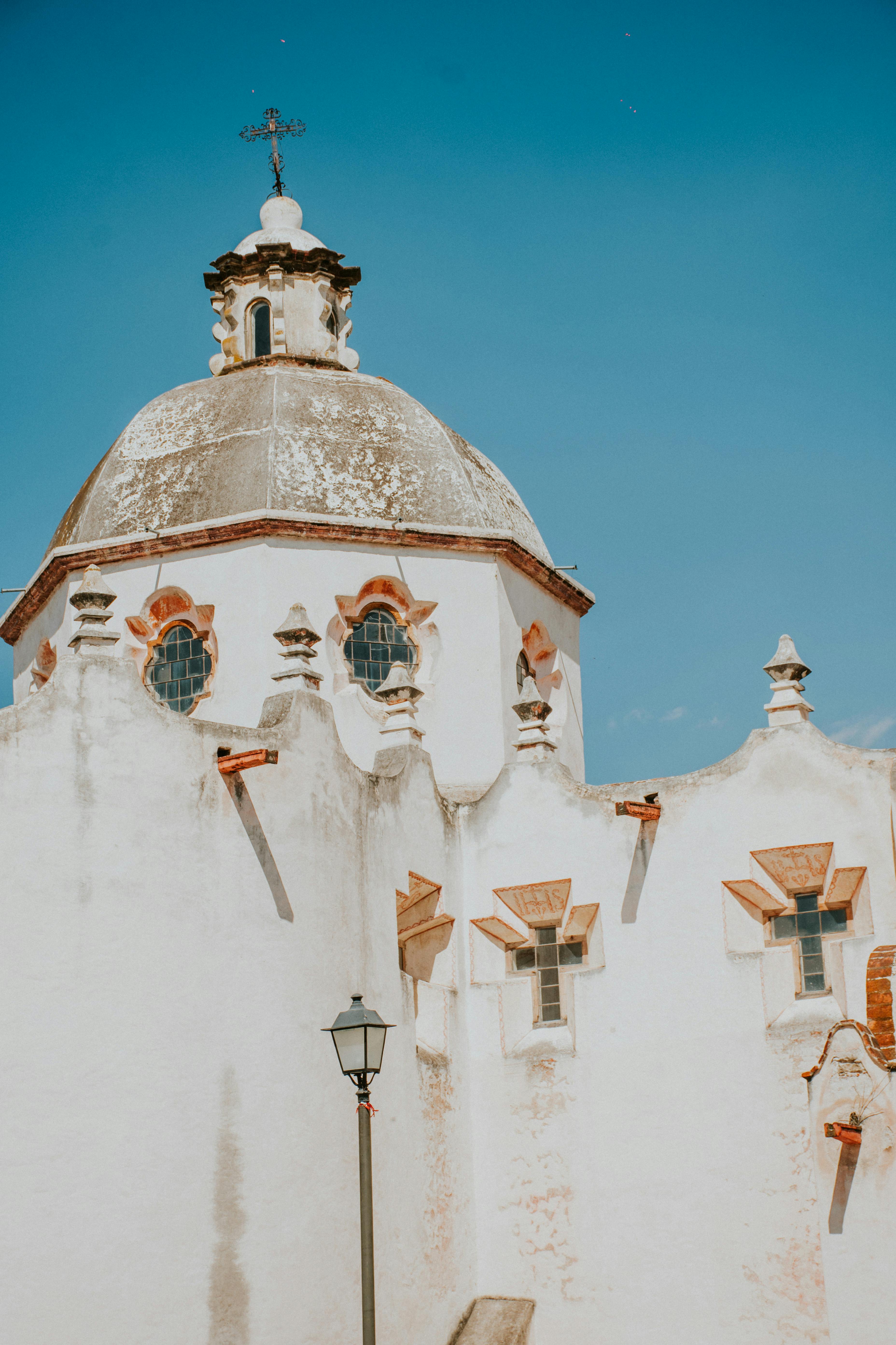 Capture of a historic baroque church with ornate dome and architecture against a clear blue sky.