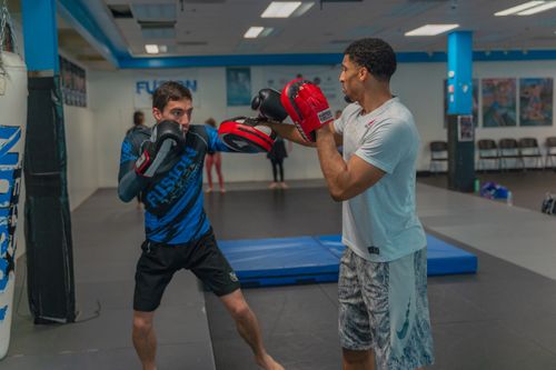 Free Two men engaged in boxing training indoors, using focus pads for practice. Stock Photo