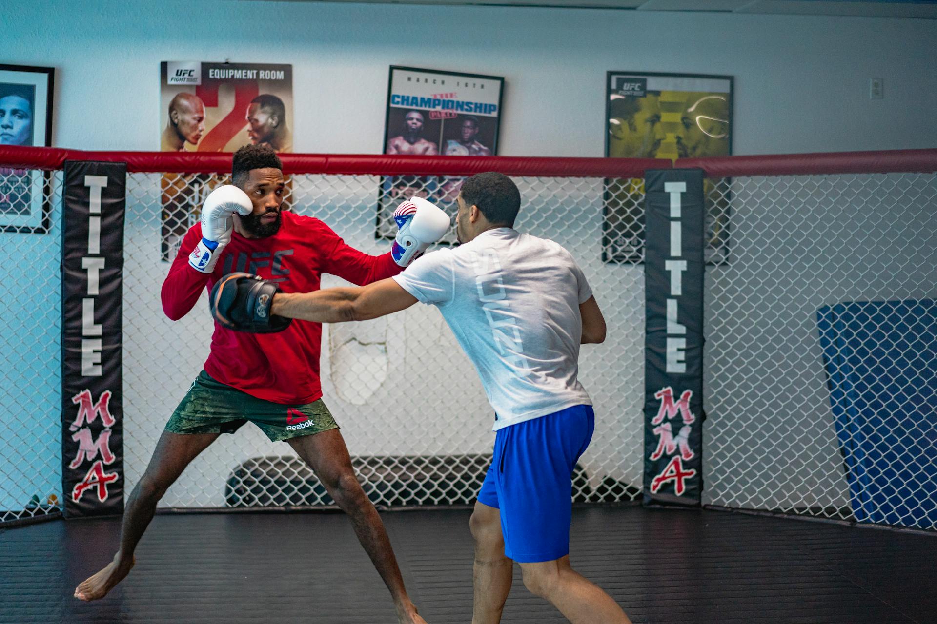 Two men engaged in an intense mixed martial arts training in an indoor gym.