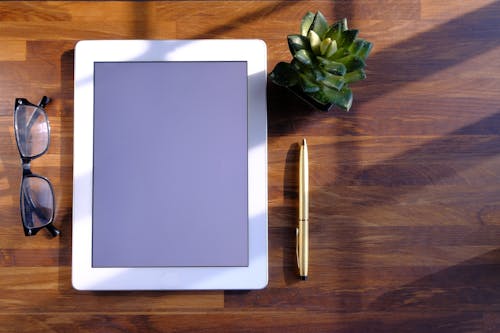 A Tablet and a Pen on a Wooden Surface