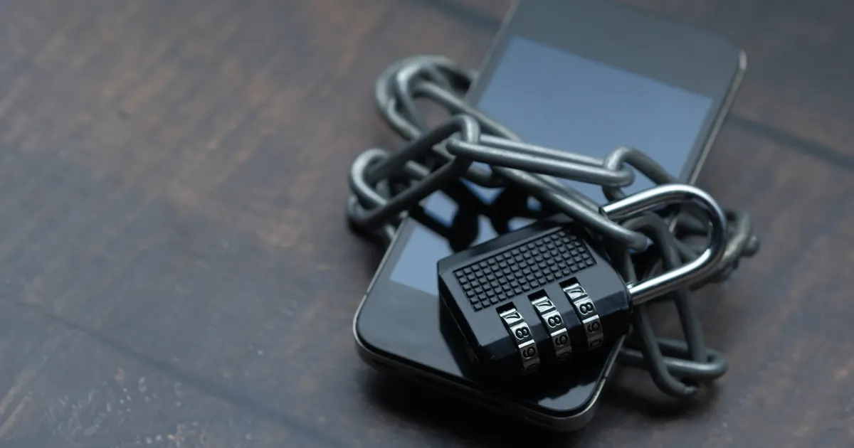 A smartphone wrapped in chains with a combination padlock on top, representing TypeScript AI agent circuit breaker and audit trail patterns