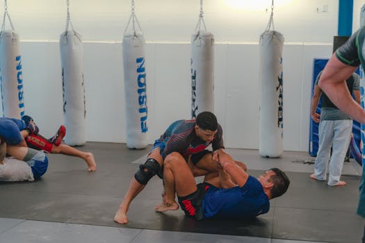 Men practicing mixed martial arts grappling in a boxing gym.