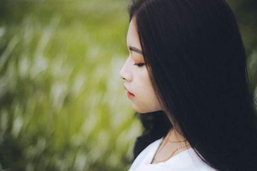 Profile view of a serene woman outdoors with blurred green background, perfect for contemplation themes.