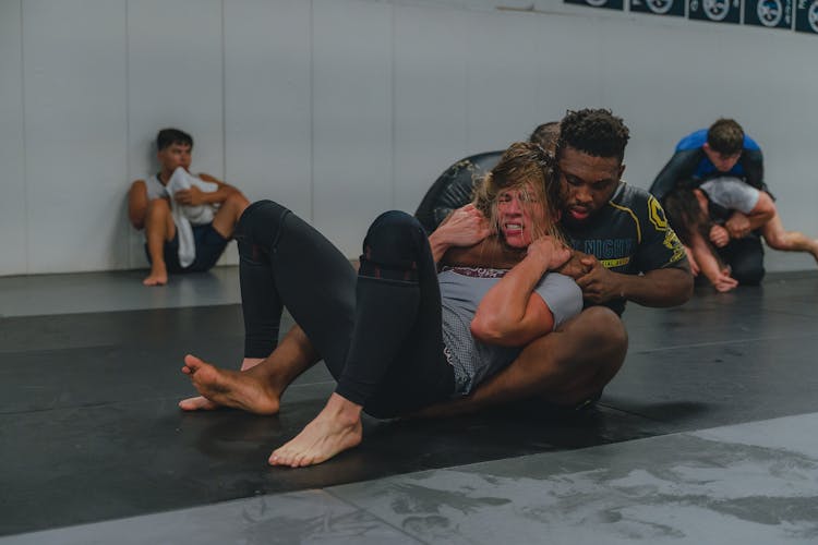 A Woman And A Man Wrestling On A Mat In A Gym