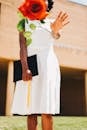 Unrecognizable ethnic woman throwing rose branch to camera