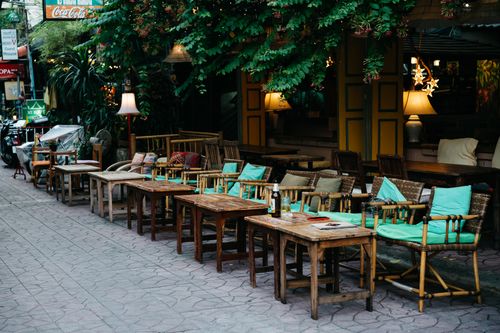 Free Charming al fresco dining setup with rustic furniture and vibrant greenery in a cozy restaurant. Stock Photo