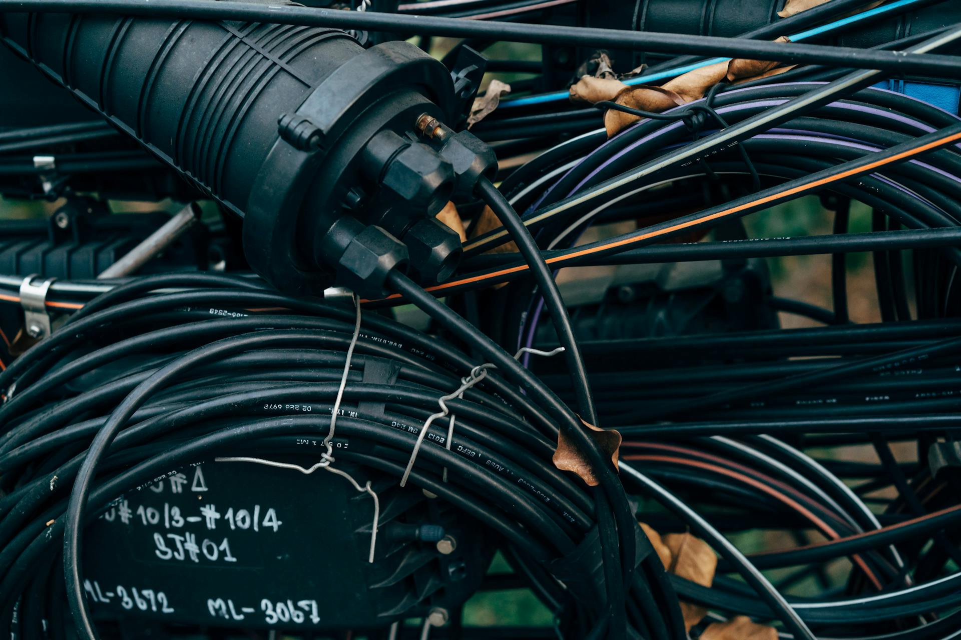 Close-up view of intertwined black cables and connectors in an outdoor telecom setup.