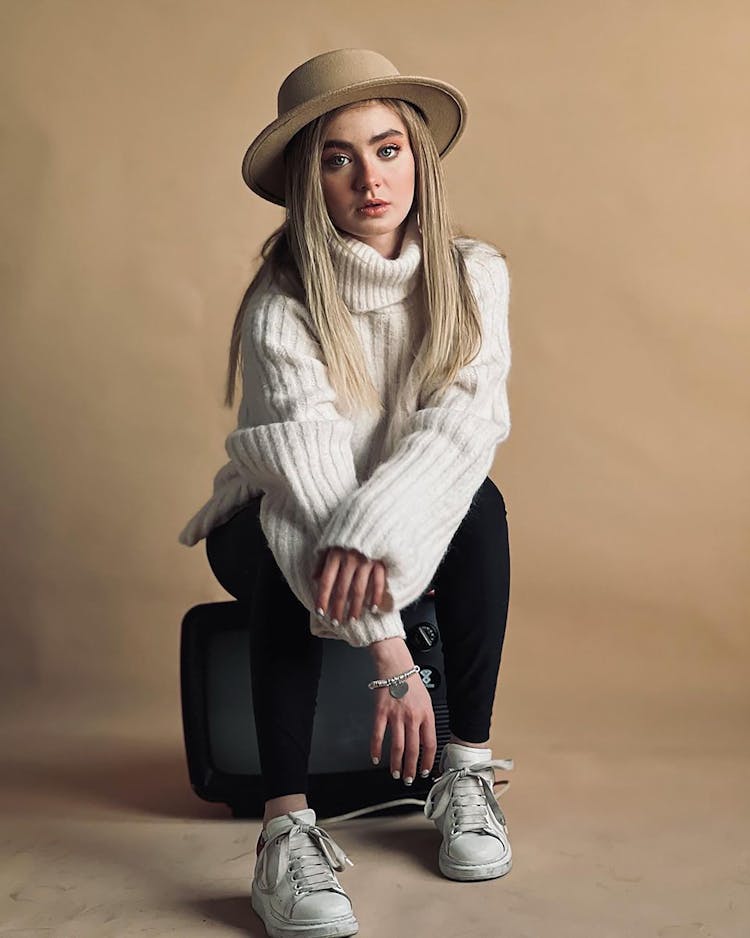 Woman Wearing Sweater Sitting On A Television