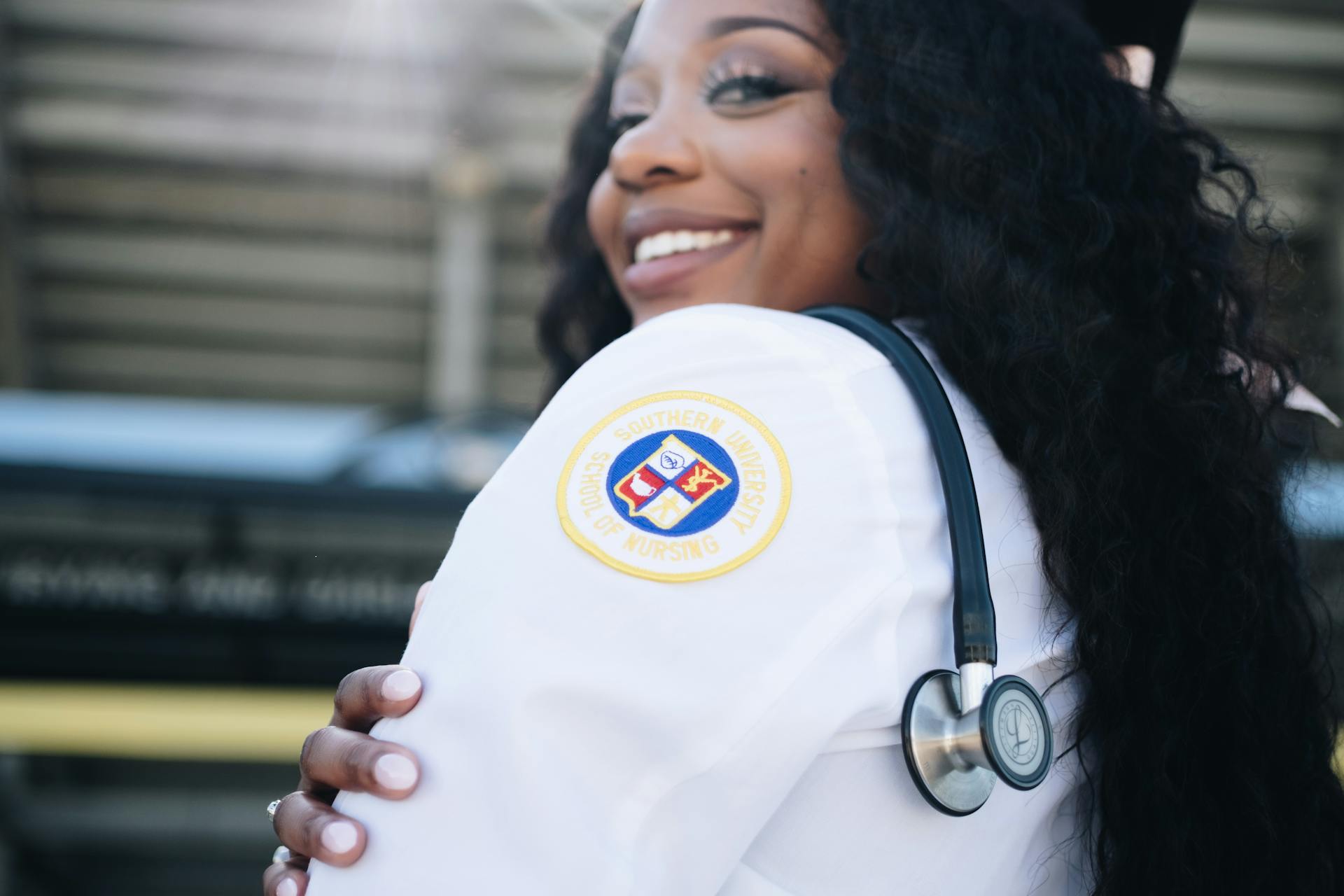 Black woman in medical uniform and stethoscope hanging over shoulder