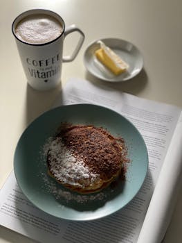 Cozy morning pancakes with coffee, butter, and reading material.