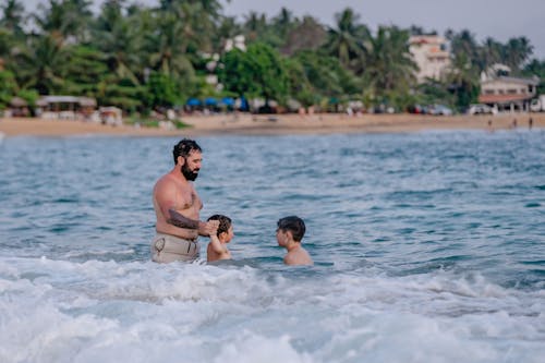 Man Swimming at the Beach with his Children