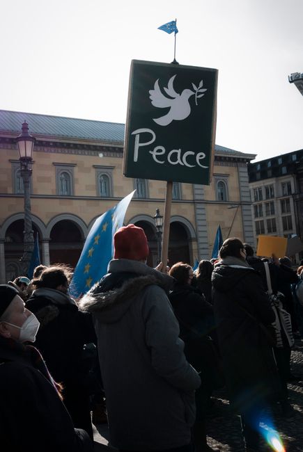A crowd in Munich holds a peace sign during a peaceful protest in the city square.