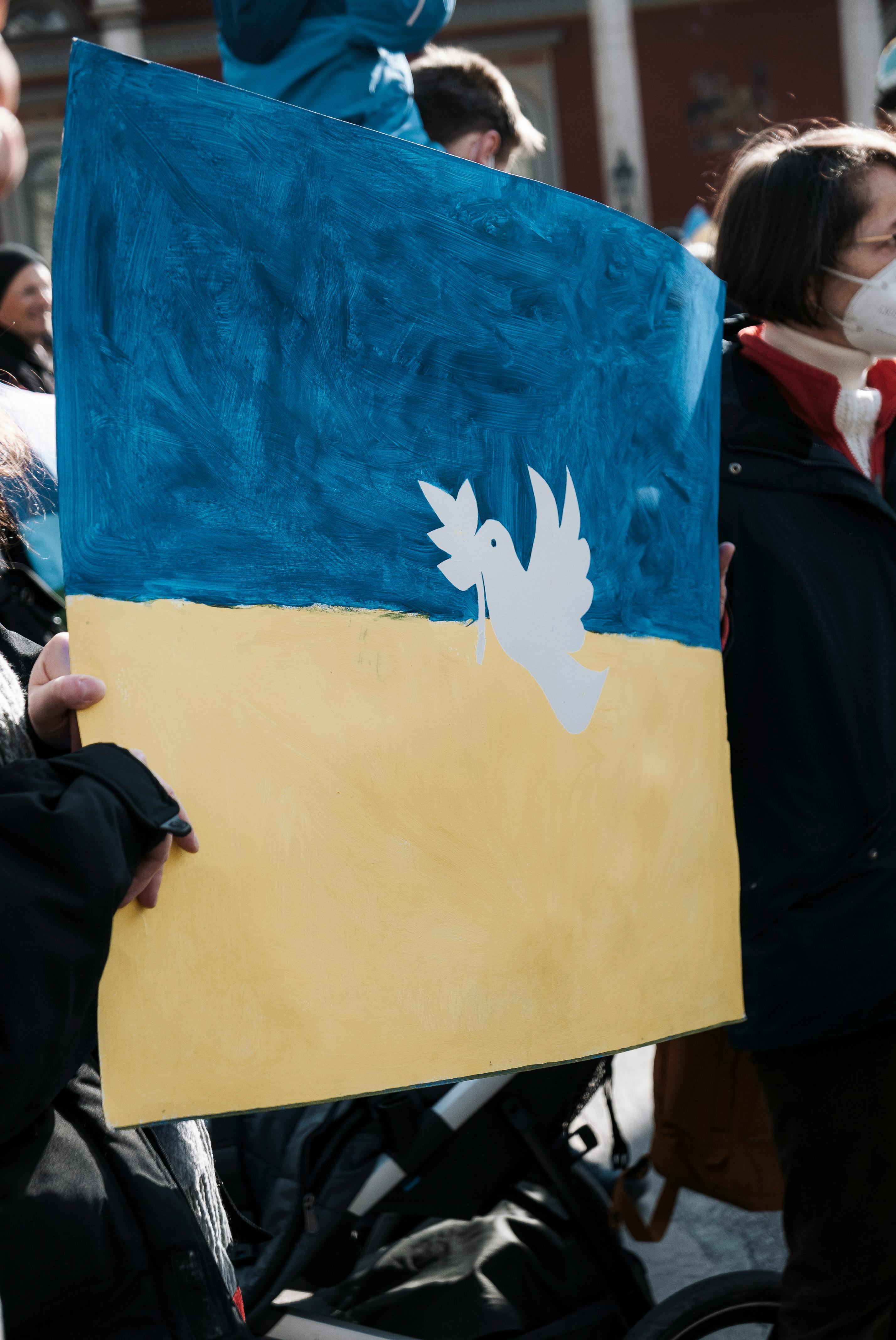 A crowd in Munich holds a peace poster depicting Ukraine's flag during a protest.