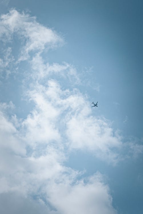 Free Airplane Flying Under White Clouds and Blue Sky Stock Photo