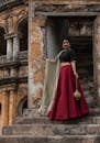 一名女子身穿鲜艳红裙和黑色衬衫，优雅地站在古代印度乡村的石楼梯上