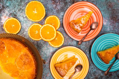 Free Close-up view of orange cake slices on colorful plates with fresh orange slices. Stock Photo