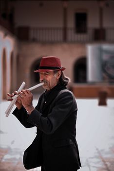 Woman in Black Coat and Red Hat Holding White Flute