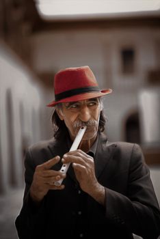Man in Black Suit Jacket and Red Hat Holding Flute