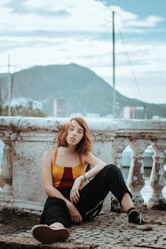 Casual portrait of a young woman sitting outdoors with a mountain view.