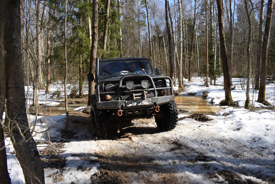 4x4 vehicle navigating snowy forest terrain, showcasing winter off-road adventure.