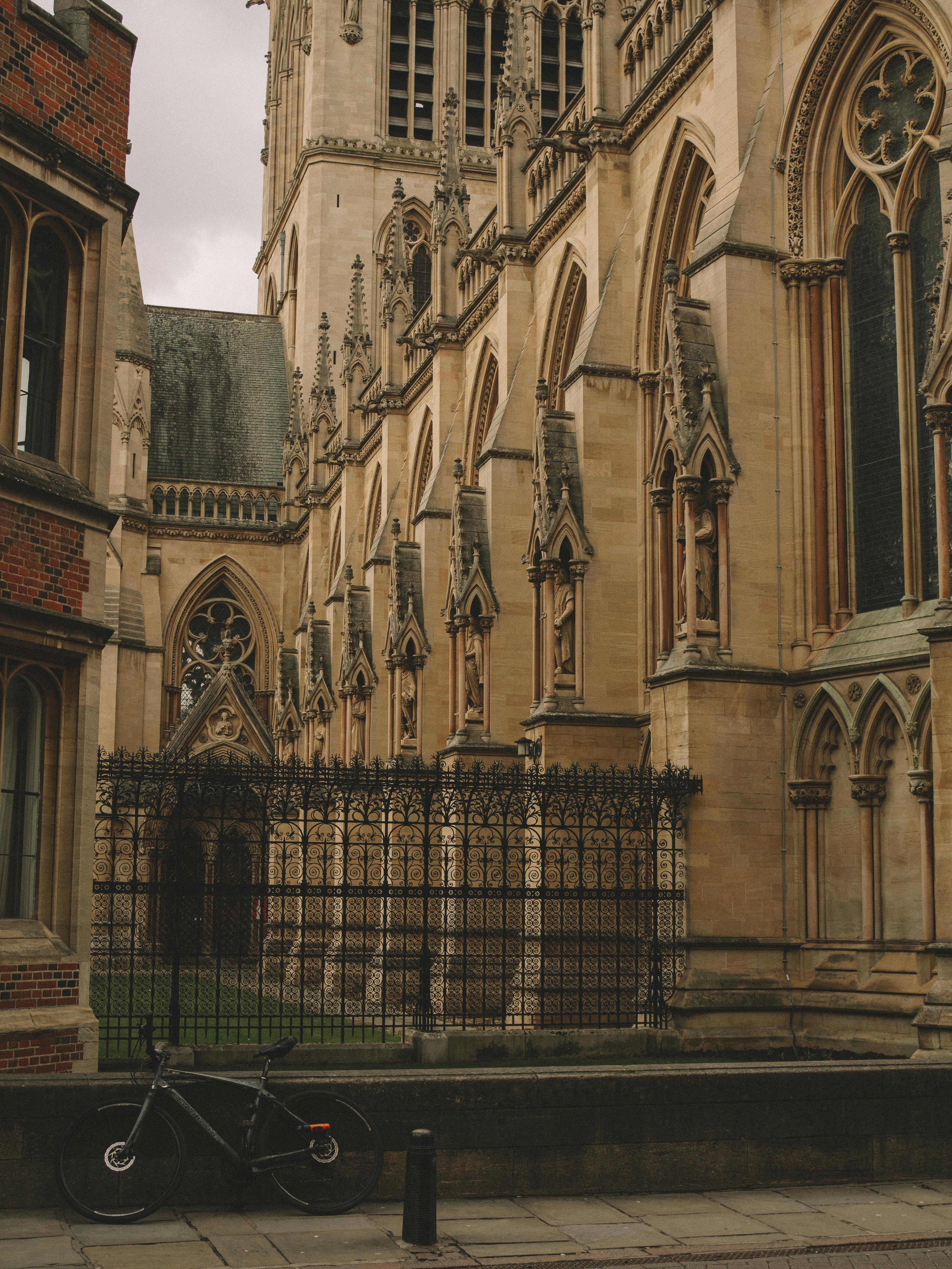 A stunning gothic cathedral exterior with a bicycle against a metal fence, ideal for architectural themes.