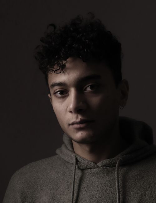 Free Dramatic low-light portrait of a young man wearing a hoodie, capturing deep emotions. Stock Photo