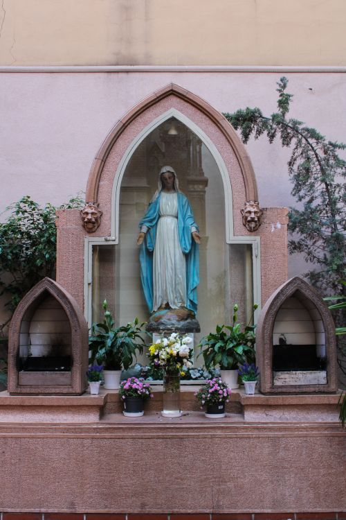 Free A serene Virgin Mary statue surrounded by flowers in a shrine in İstanbul, Turkey. Stock Photo