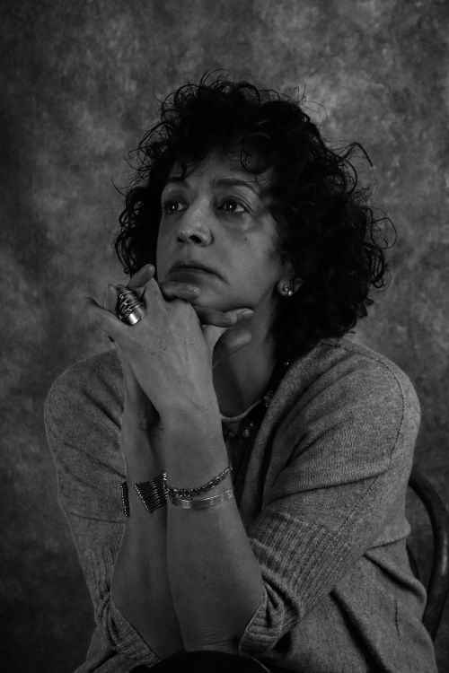 Free Moody black and white studio portrait of a thoughtful mature woman with hands under chin. Stock Photo