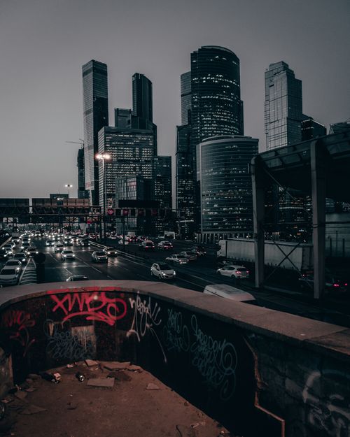 Free A vibrant urban skyline with bustling traffic and towering skyscrapers at dusk. Graffiti foreground adds depth. Stock Photo