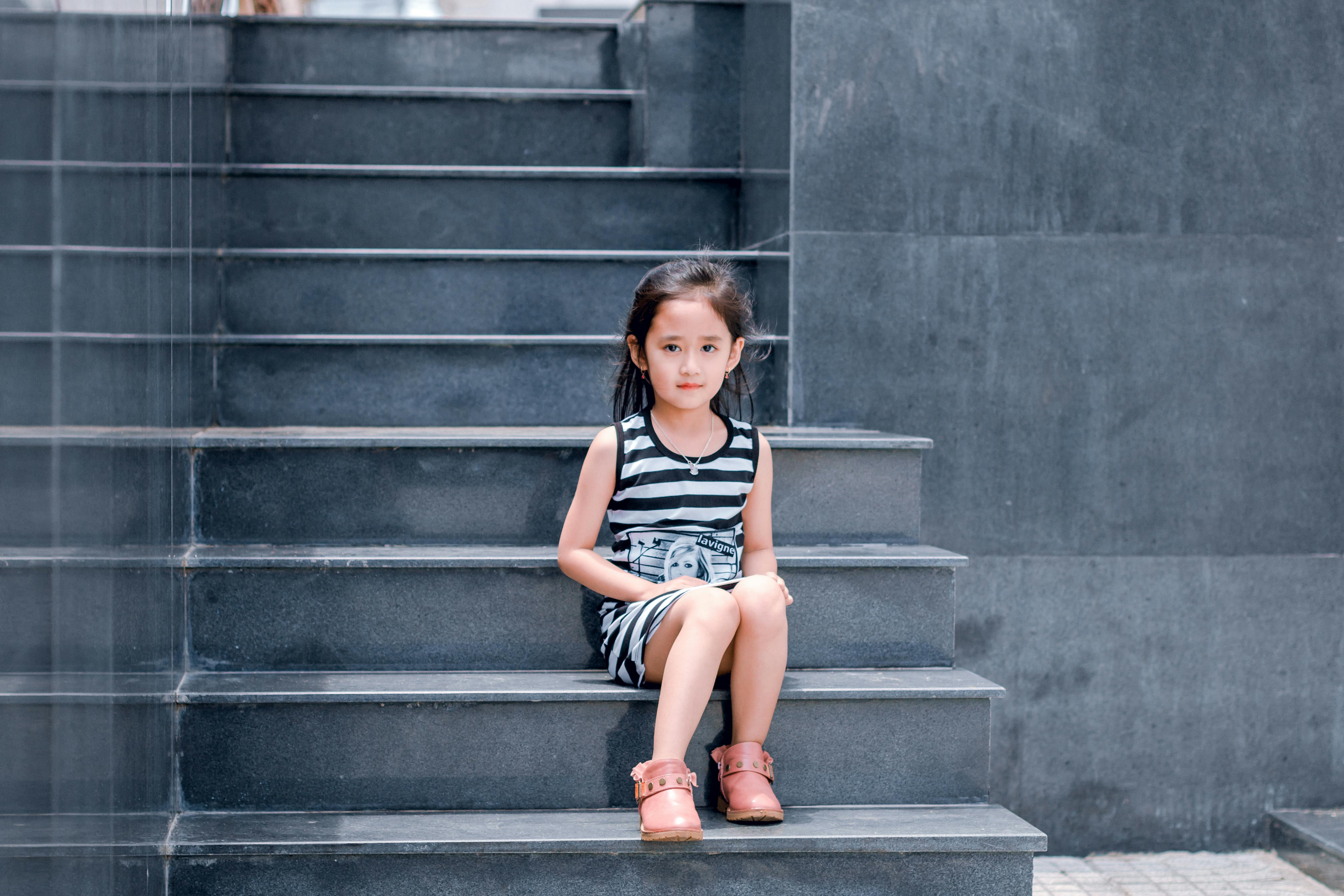 girl wearing black and white striped dress sitting on stair
