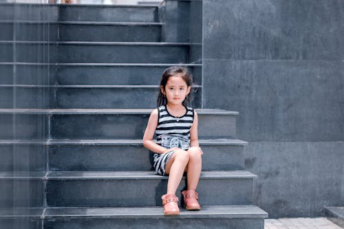 Girl Wearing Black and White Striped Dress Sitting on Stair