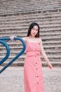 一位身着红色连衣裙的时尚年轻女子在户外台阶上摆出休闲时尚的姿势